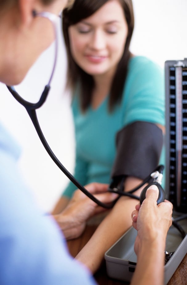 Blood pressure measurement. General practice doctor using a sphygmomanometer and stethoscope to measure a young female patient's blood pressure. Blood pressure is an important measure of health. High blood pressure (hypertension) puts a great deal of stra