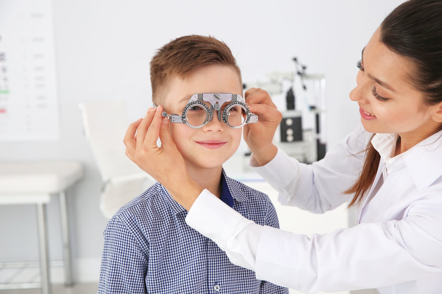 Children's Doctor Putting Trial Frame on Little Boy in Clinic. Eye Examination